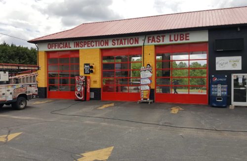 auto body shop with 3 red industrial doors after professional garage door installation